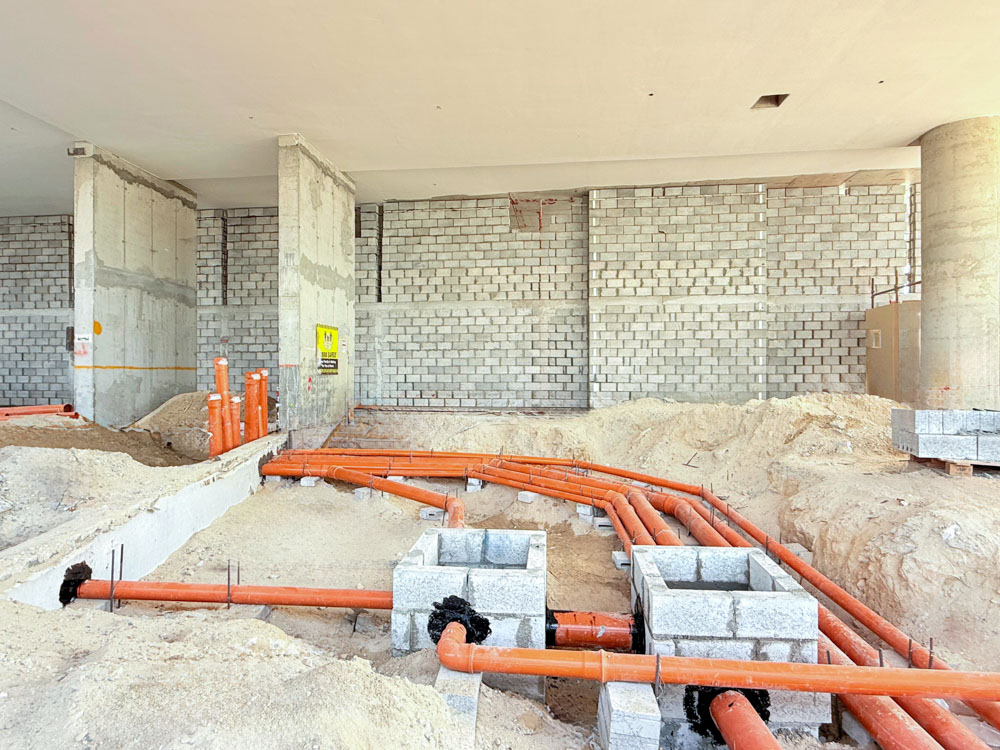 Beach Walk Iii By Imtiaz Interior construction site featuring concrete walls, orange pipes on a sandy floor, and building foundations.